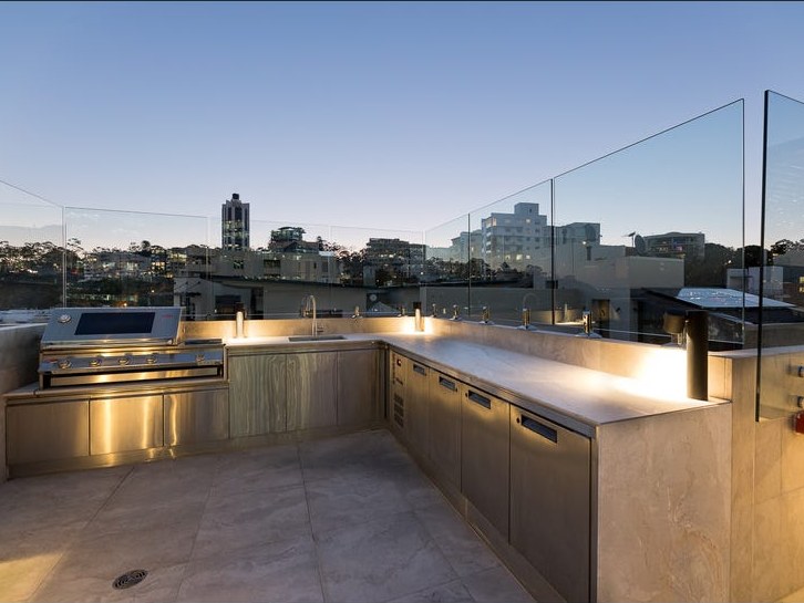 Outdoor kitchen with barbecue, sink and stone benchtops on the rooftop