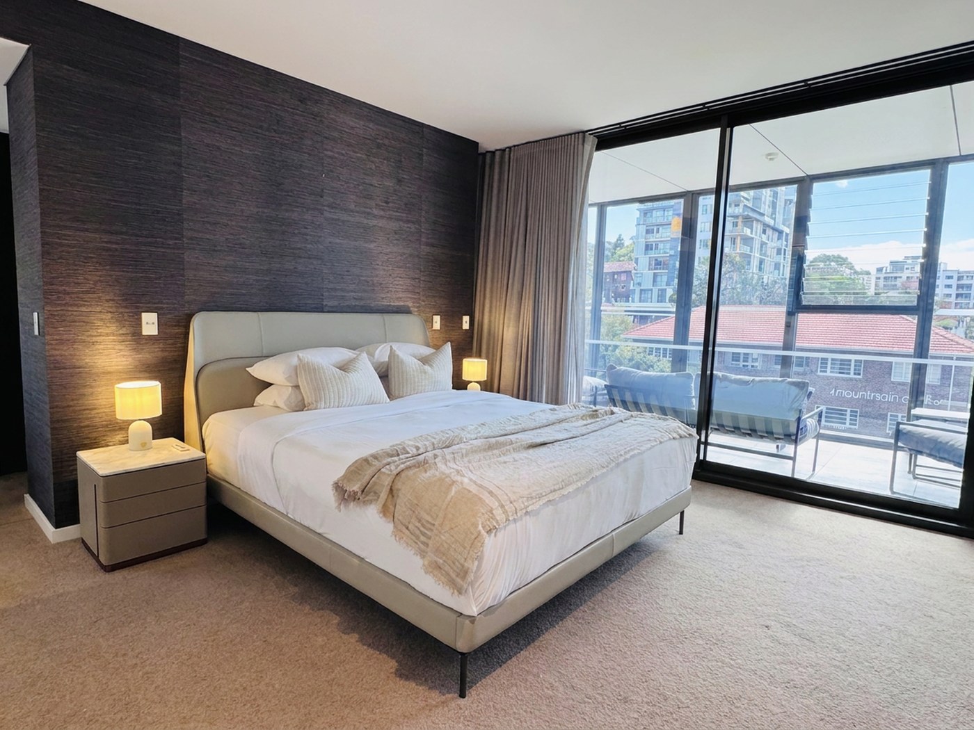 Master suite with textured feature wall and floor-to-ceiling glazing opening to a private balcony