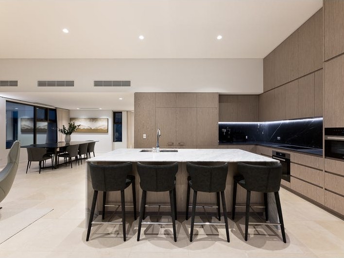 Open-plan kitchen and dining area with stone island bench and seating for four