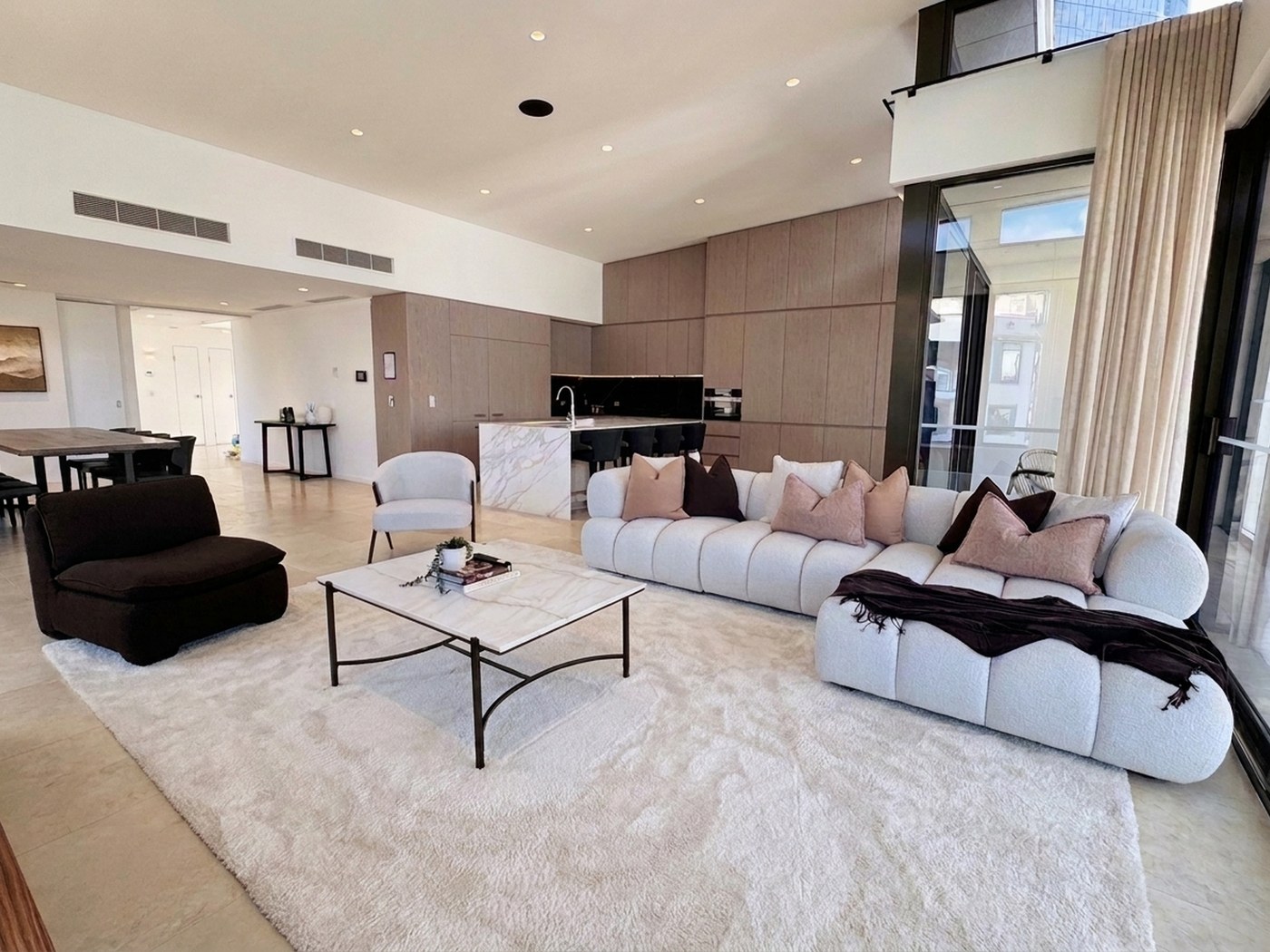 Open-plan living area with full-height glazing, marble island and lounge seating