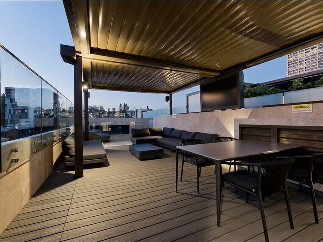 Covered rooftop terrace with timber pergola, lounge seating and outdoor dining at dusk